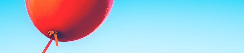 Das Bild zeigt einen einzelnen roten Luftballon vor blauem Himmel